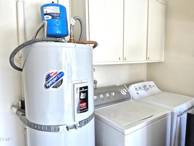 clothes washing area featuring cabinets, washer and dryer, and secured water heater