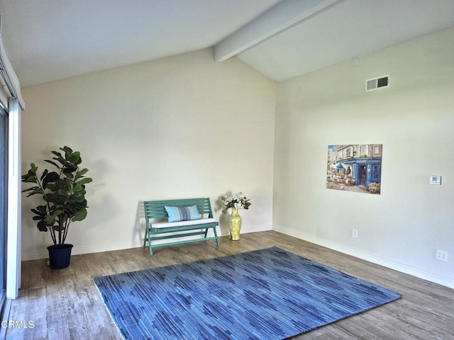 living area featuring hardwood / wood-style flooring and vaulted ceiling with beams