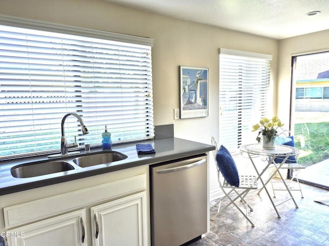 kitchen featuring sink, stainless steel dishwasher, and a textured ceiling