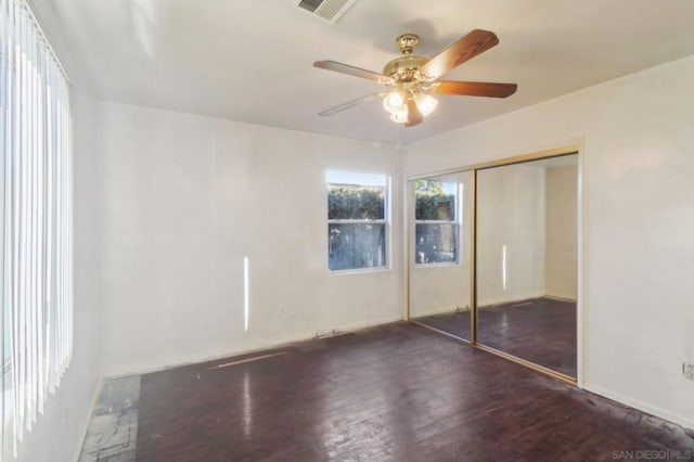 unfurnished bedroom with dark wood-type flooring, ceiling fan, and a closet