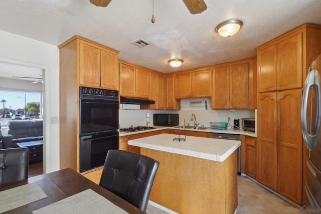 kitchen featuring a kitchen island with sink, sink, black appliances, and ceiling fan