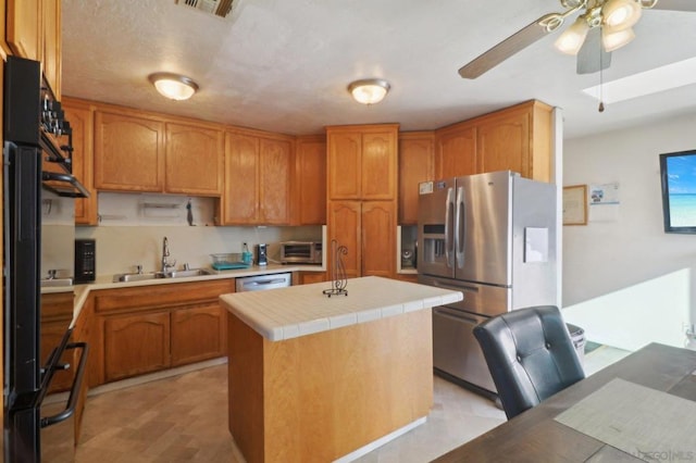 kitchen with ceiling fan, appliances with stainless steel finishes, a center island, and sink