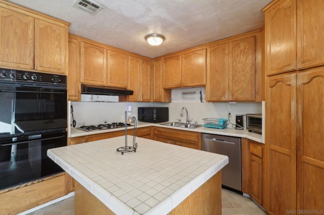 kitchen featuring sink, black appliances, an island with sink, a textured ceiling, and tile countertops