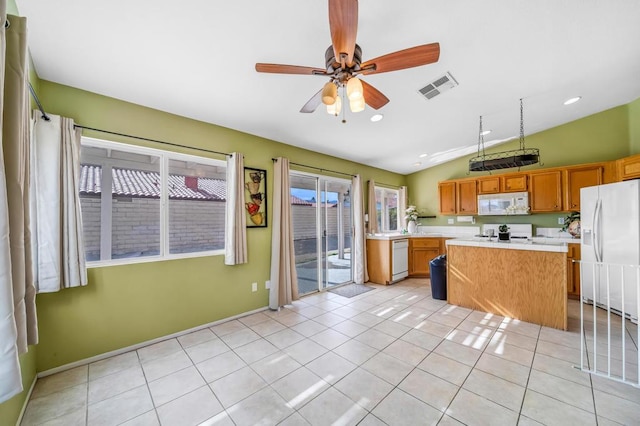 kitchen featuring lofted ceiling, white appliances, a center island, light tile patterned floors, and ceiling fan