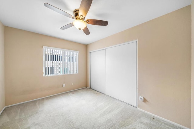 unfurnished bedroom with light colored carpet, ceiling fan, and a closet