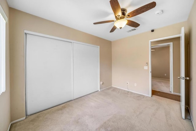 unfurnished bedroom featuring ceiling fan, light carpet, and a closet