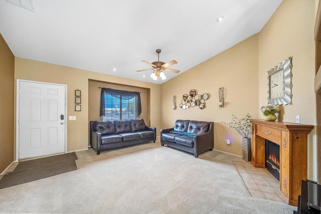 living room with light colored carpet, vaulted ceiling, a tile fireplace, and ceiling fan