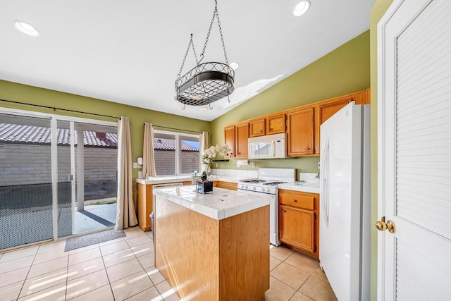 kitchen featuring lofted ceiling, a center island, tile counters, light tile patterned floors, and white appliances