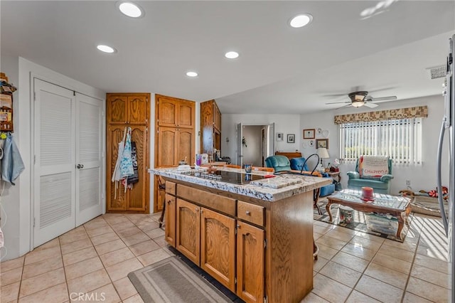 kitchen with light tile patterned flooring, a center island, black electric stovetop, and ceiling fan