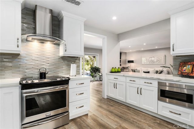 kitchen featuring white cabinetry, stainless steel electric range, and wall chimney range hood