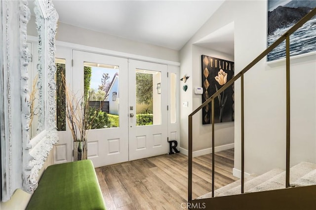 foyer with lofted ceiling, french doors, and light wood-type flooring