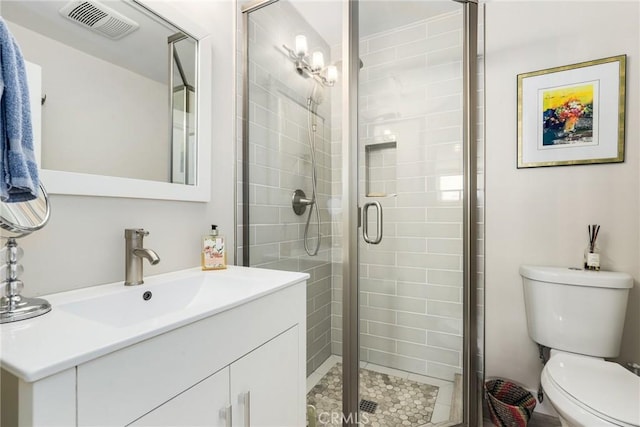 bathroom featuring vanity, a shower with door, and toilet