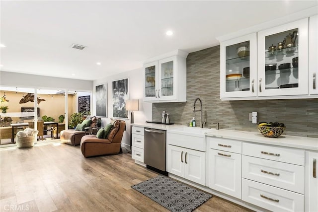 kitchen featuring white cabinetry, sink, backsplash, stainless steel dishwasher, and light hardwood / wood-style flooring