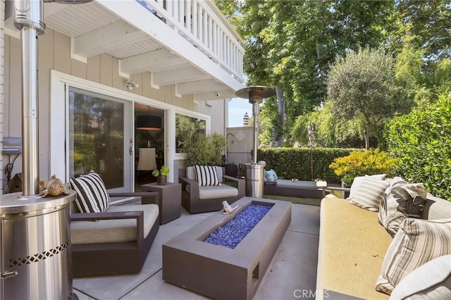 view of patio featuring a balcony and an outdoor living space with a fire pit