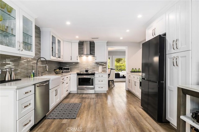 kitchen with white cabinetry, appliances with stainless steel finishes, and wall chimney range hood