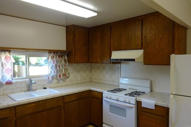 kitchen with sink, white appliances, tasteful backsplash, tile countertops, and exhaust hood