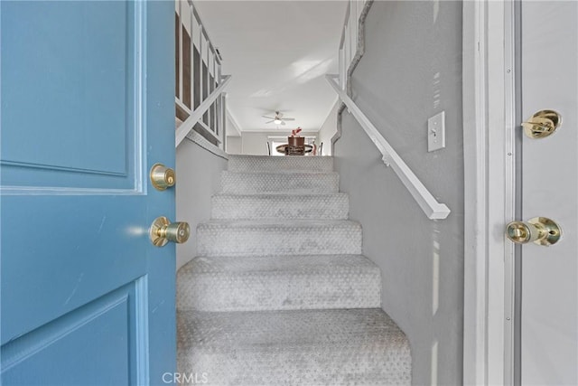 stairs featuring ceiling fan