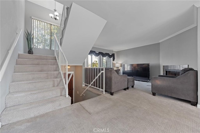 staircase featuring crown molding, carpet flooring, a notable chandelier, and a fireplace