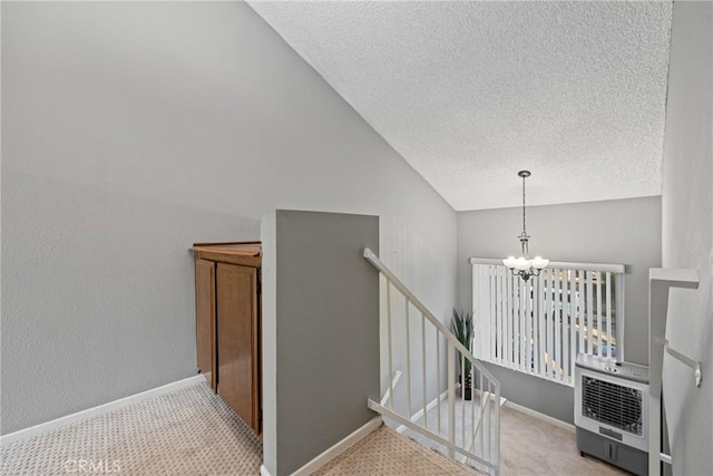 staircase featuring carpet, heating unit, a textured ceiling, and an inviting chandelier