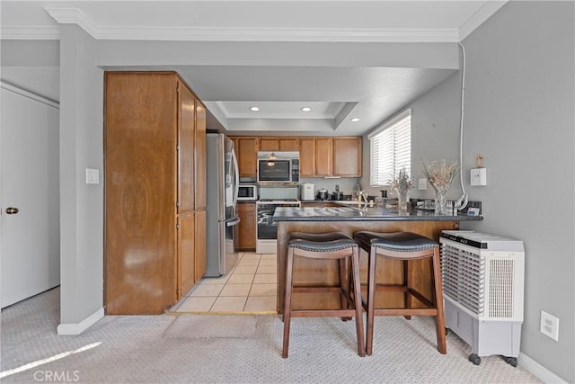 kitchen with a breakfast bar, appliances with stainless steel finishes, kitchen peninsula, and ornamental molding