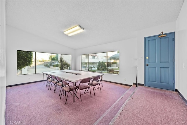 carpeted dining room featuring lofted ceiling and a textured ceiling