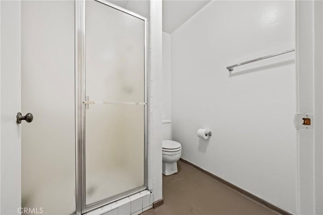 bathroom featuring a shower with door and toilet