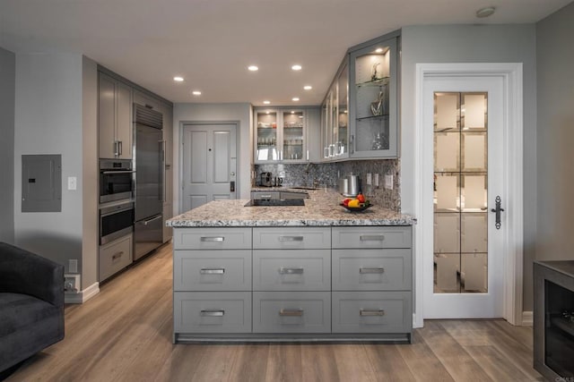 kitchen with gray cabinets, appliances with stainless steel finishes, electric panel, and light stone counters