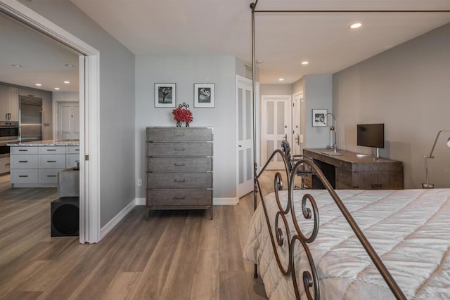 bedroom featuring hardwood / wood-style flooring, stainless steel built in refrigerator, and connected bathroom