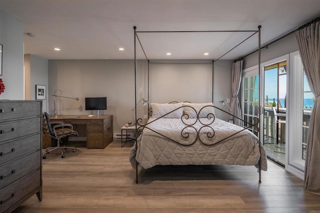 bedroom featuring light hardwood / wood-style flooring, a baseboard heating unit, and access to outside