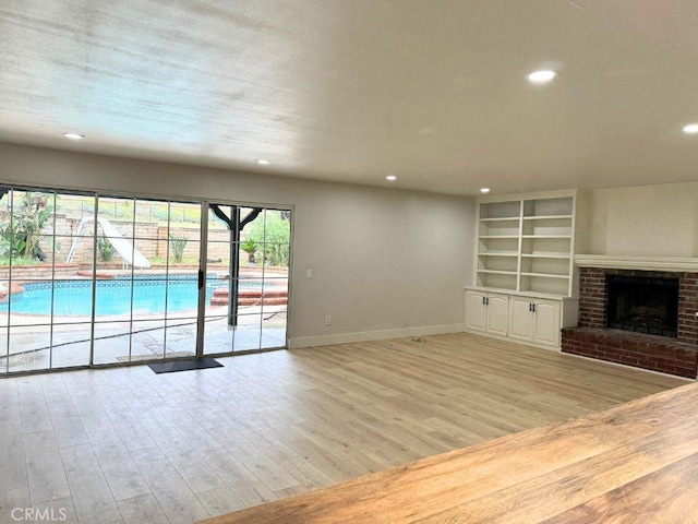 20591 Celtic St, Chatsworth, CA 91311 - unfurnished living room featuring light wood-style floors, baseboards, recessed lighting, a fireplace, and built in shelves