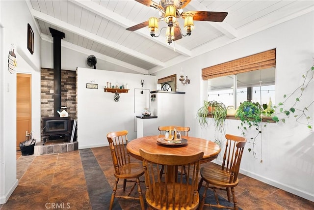 dining area featuring lofted ceiling with beams, a wood stove, and ceiling fan