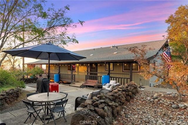 back house at dusk featuring a patio