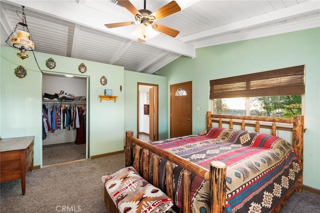 carpeted bedroom with ceiling fan, a walk in closet, a closet, and vaulted ceiling with beams