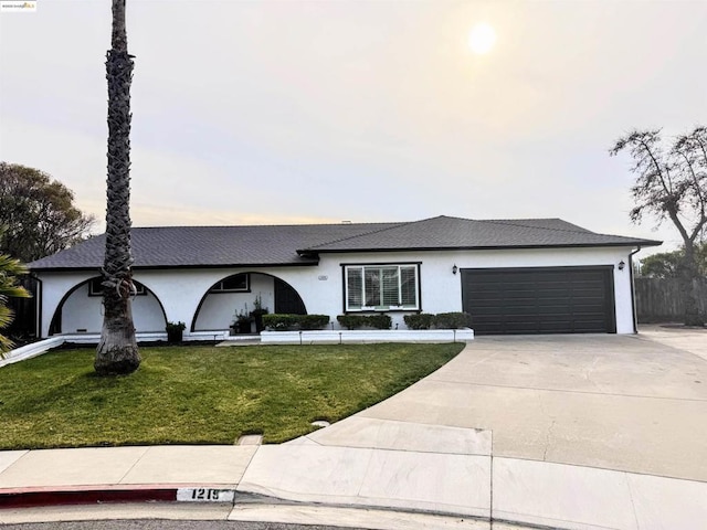 ranch-style house featuring a garage and a front lawn