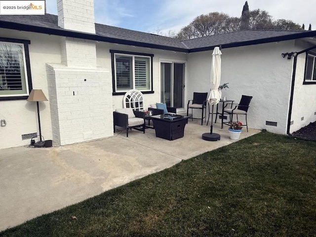 rear view of property with a lawn, a patio, and an outdoor living space with a fire pit