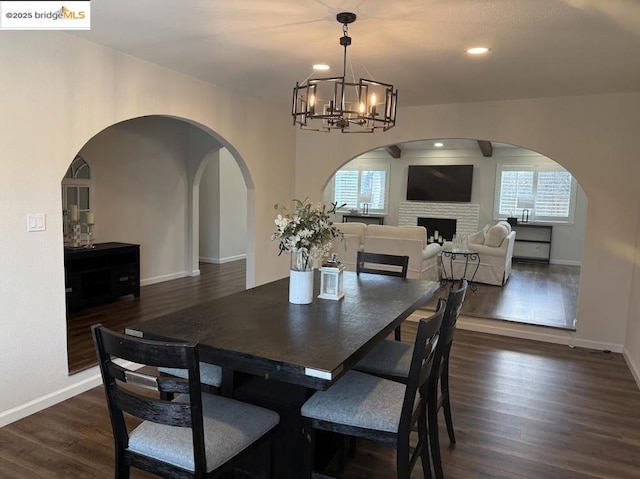 dining space with dark wood-type flooring, a wealth of natural light, and a chandelier