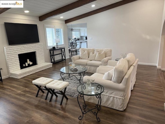 living room with dark hardwood / wood-style floors, beam ceiling, a brick fireplace, and wooden ceiling