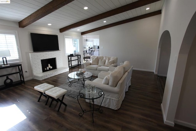 living room with beamed ceiling, a brick fireplace, and dark hardwood / wood-style flooring