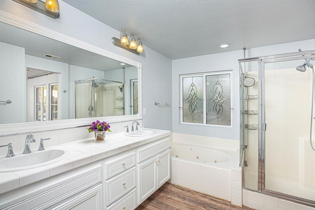 bathroom with a tub with jets, a sink, visible vents, and a shower stall