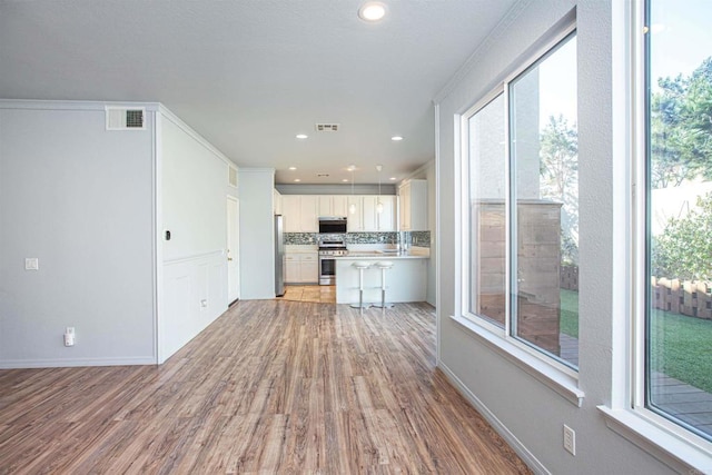 kitchen with light countertops, visible vents, backsplash, appliances with stainless steel finishes, and light wood-style floors