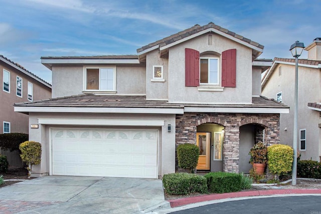 traditional-style house with an attached garage, stone siding, concrete driveway, and stucco siding