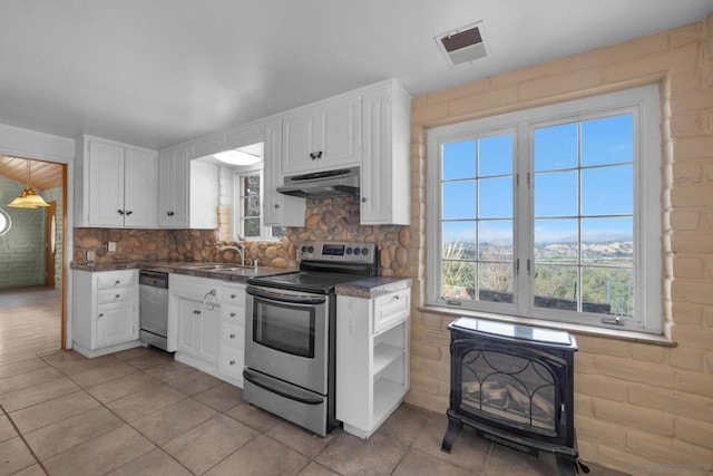 kitchen featuring appliances with stainless steel finishes, a wood stove, and white cabinets