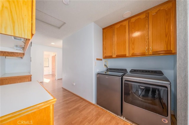 washroom with cabinets, independent washer and dryer, and light hardwood / wood-style floors