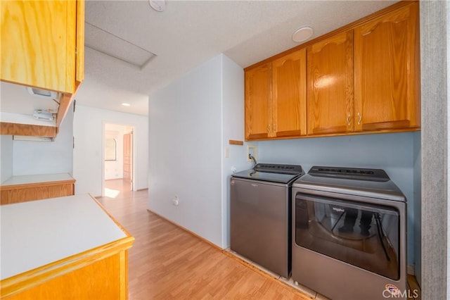 laundry area featuring light wood-style flooring, recessed lighting, cabinet space, and washer and dryer