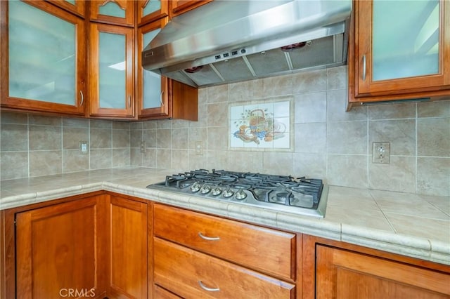 kitchen with ventilation hood, stainless steel gas cooktop, and backsplash