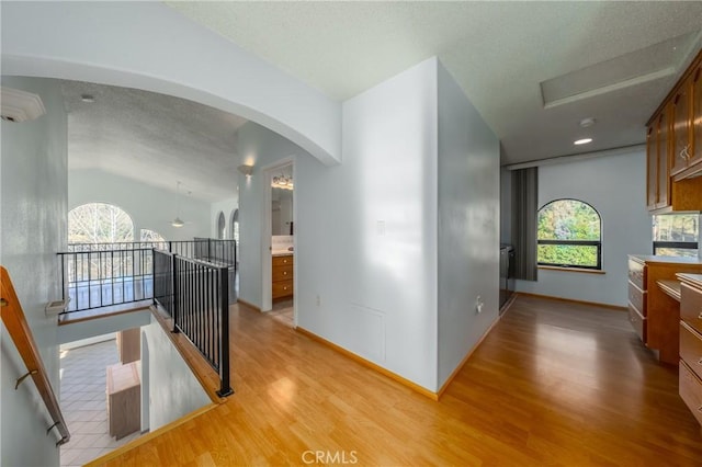 15796 Joseph Trl, Lower Lake, CA 95457 - corridor featuring light wood finished floors, an AC wall unit, a textured ceiling, arched walkways, and an upstairs landing