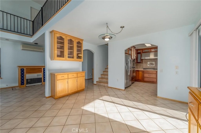 kitchen featuring decorative backsplash, glass insert cabinets, under cabinet range hood, arched walkways, and stainless steel appliances