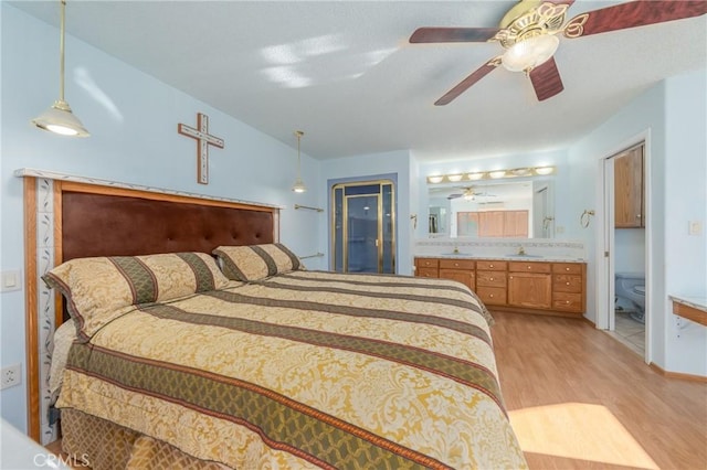 bedroom featuring sink, ensuite bath, ceiling fan, and light wood-type flooring