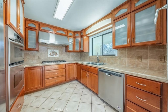 15796 Joseph Trl, Lower Lake, CA 95457 - kitchen with appliances with stainless steel finishes, range hood, brown cabinetry, glass insert cabinets, and backsplash