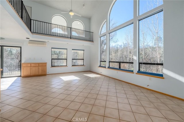 unfurnished living room featuring an AC wall unit, a ceiling fan, light tile patterned floors, and a high ceiling